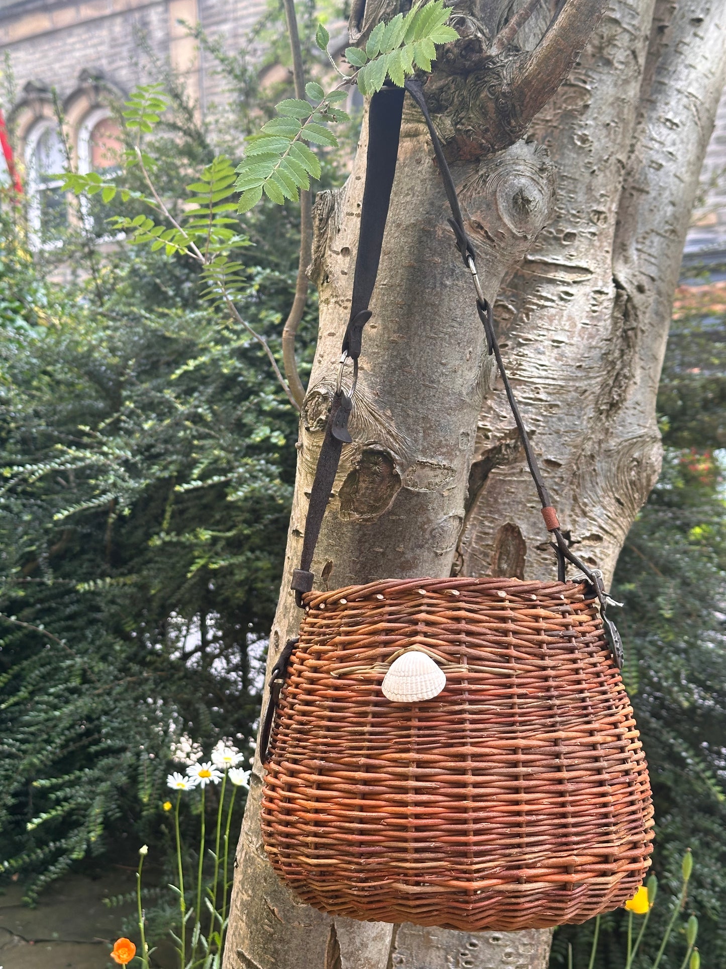 Willow handbag with a shell attached to a tree trunk in an outdoor setting