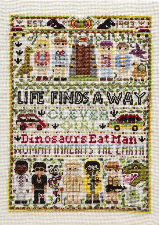 Cross-stitched design with characters and text on a white background
