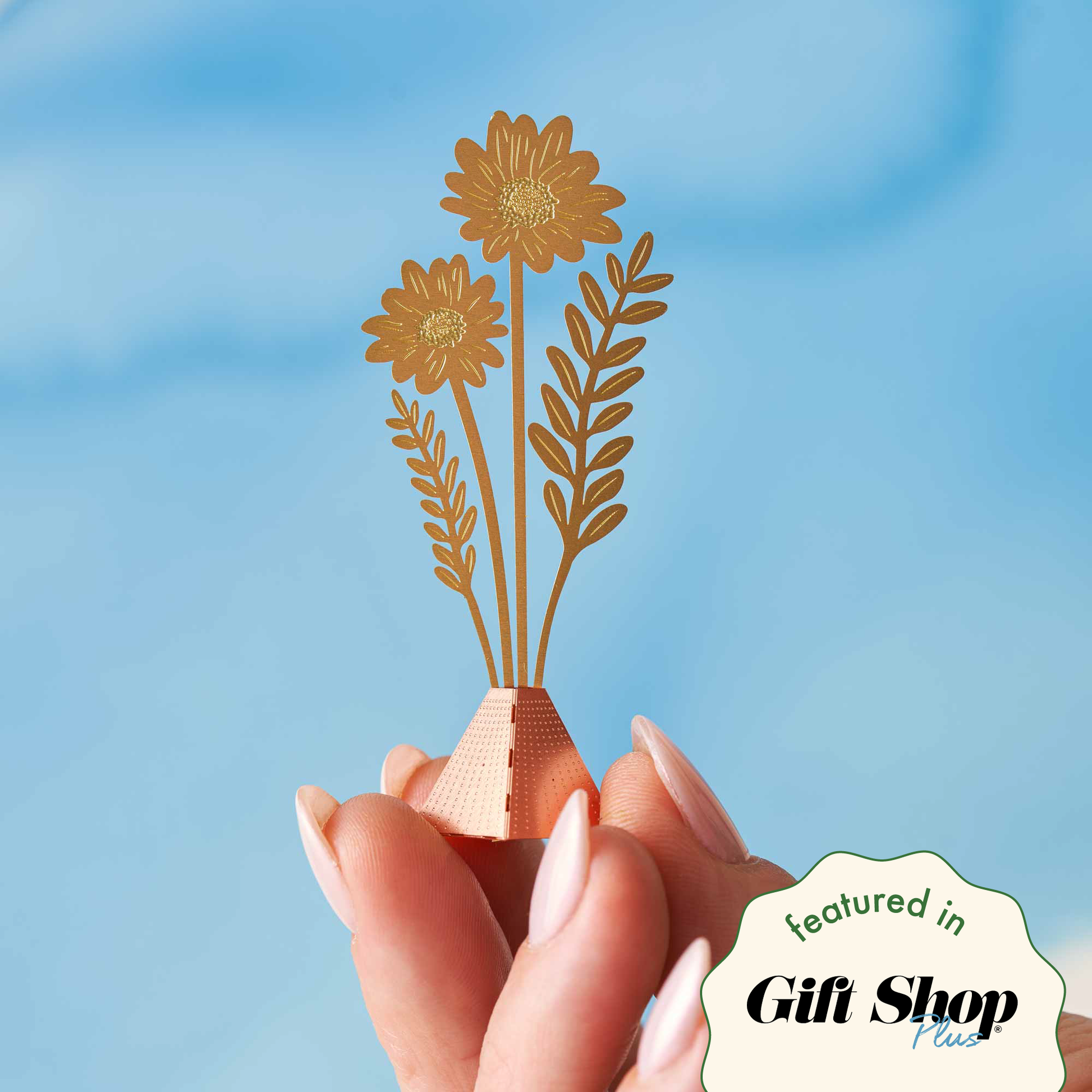A person holding a small decorative bouquet with copper or brass flowers, with a 'featured in Gift Shop' text overlay.