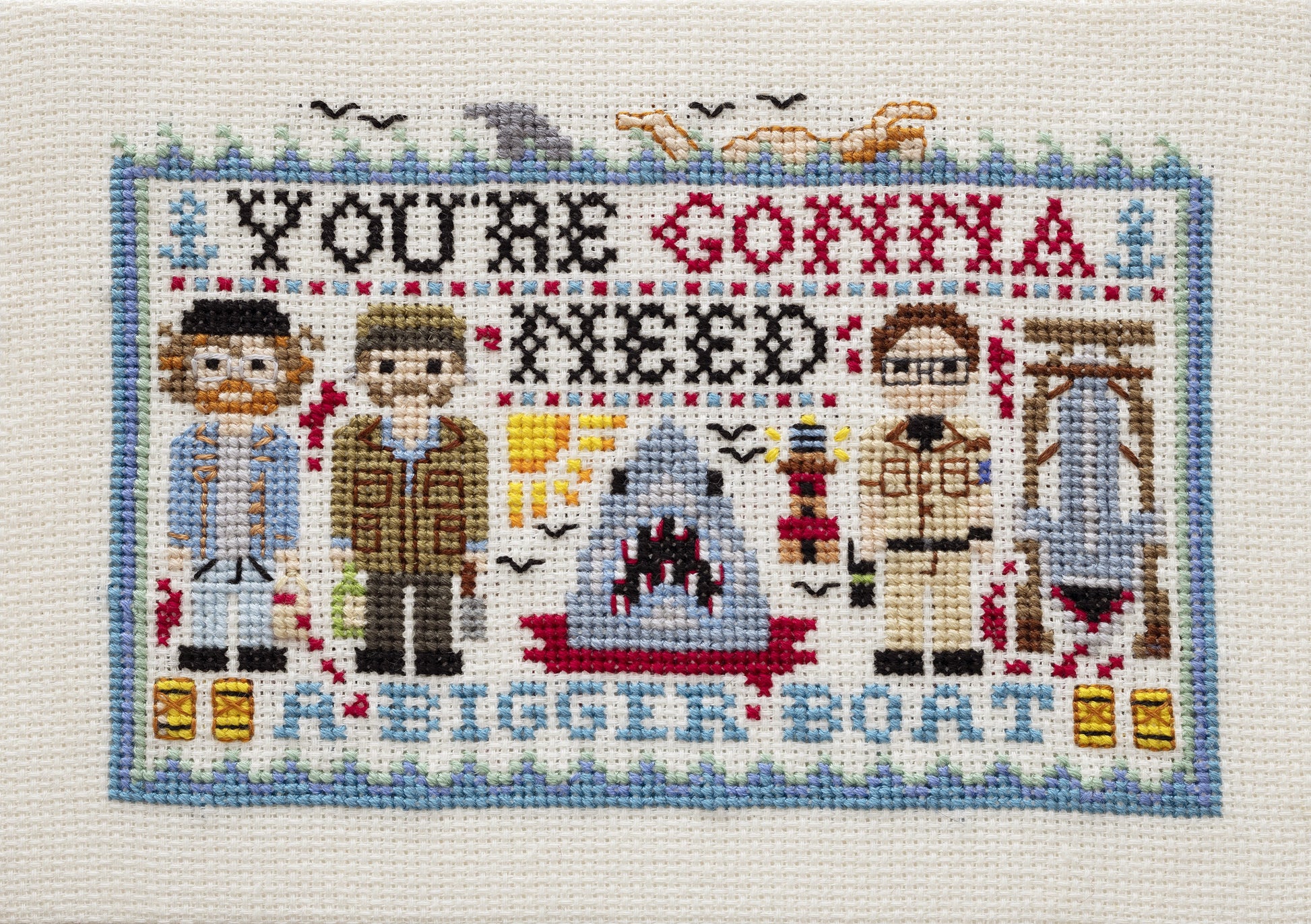 Cross-stitched panel with characters and text 'You're Gonna Need a Bigger Boat' on a white background