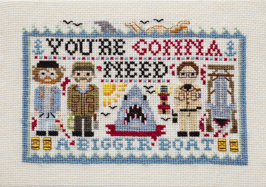 Cross-stitched panel with characters and text 'You're Gonna Need a Bigger Boat' on a white background