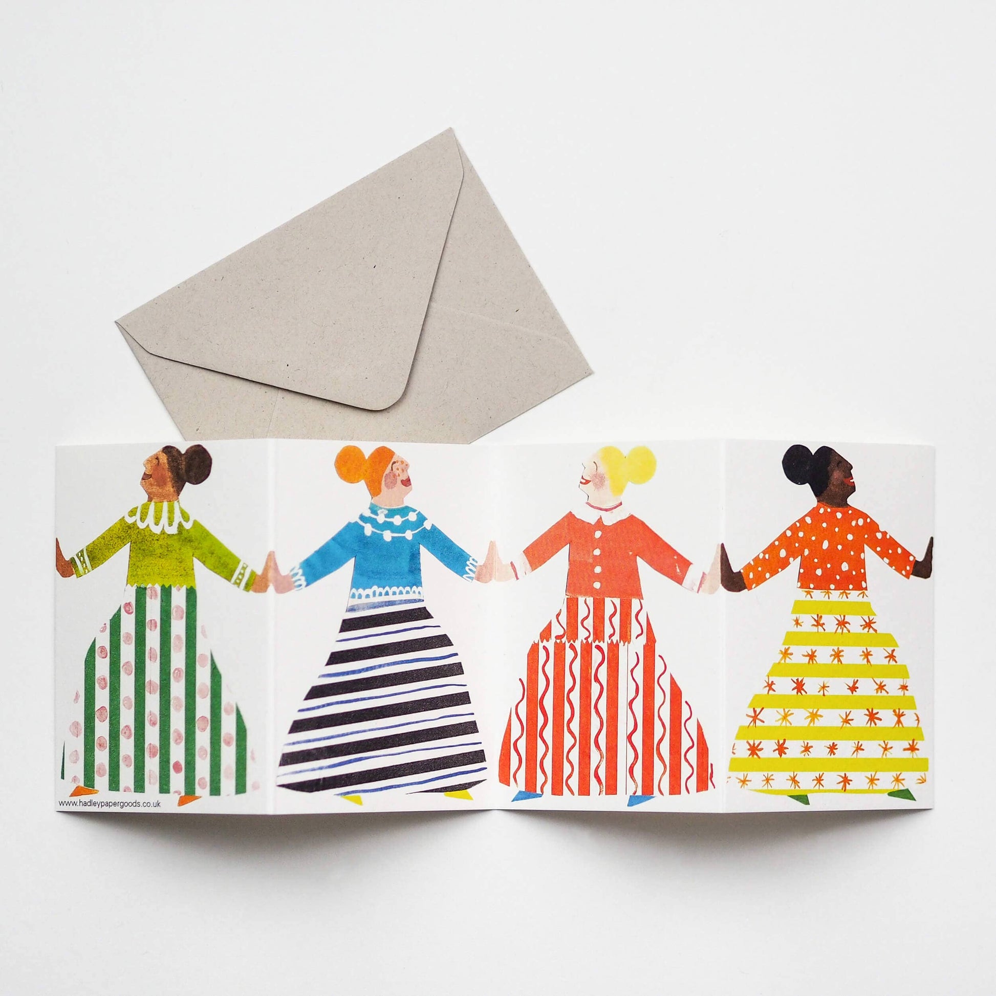 Greeting card with four women holding hands and a beige envelope on a white background