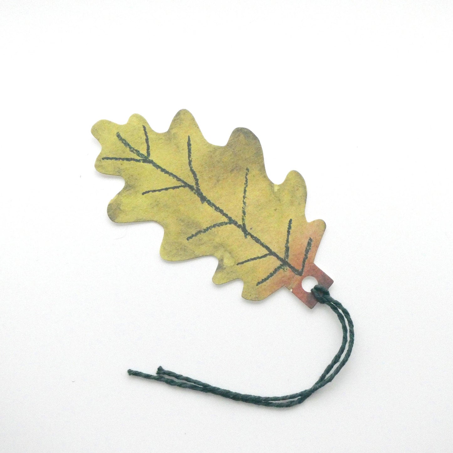 Leaf-shaped gift tag with a string on a white background