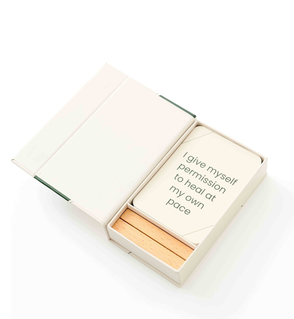 A cream-colored card set in a matching box, featuring a card that reads 'I give myself permission to heal at my own pace' and three wooden matchsticks inside a clean white background.