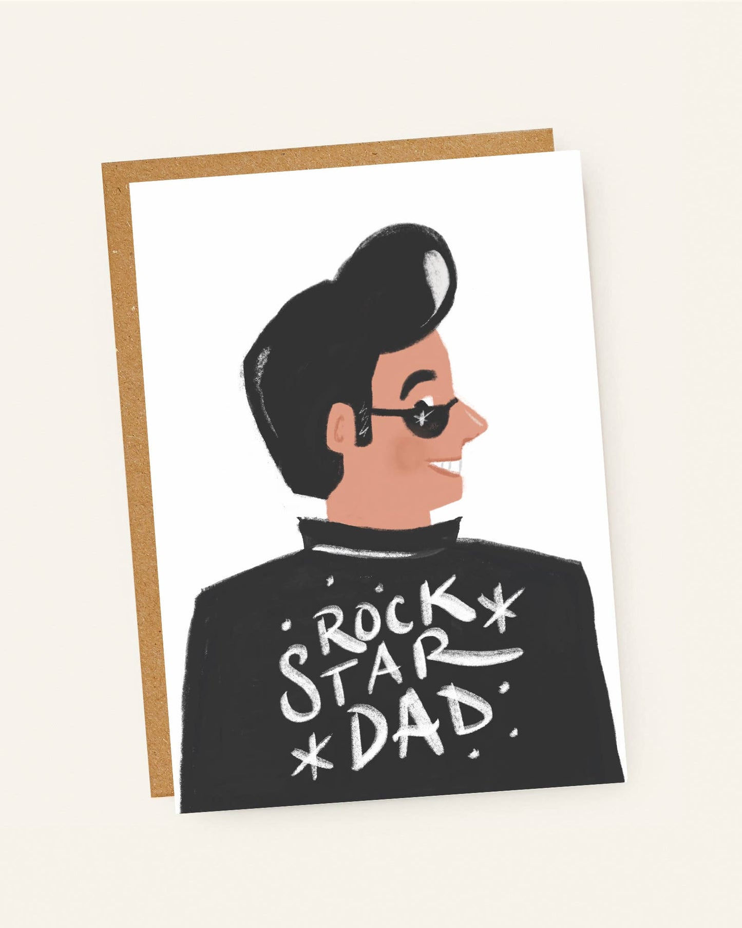 Greeting card with illustration of a person wearing sunglasses and 'Rock Star Dad' shirt on a beige background.