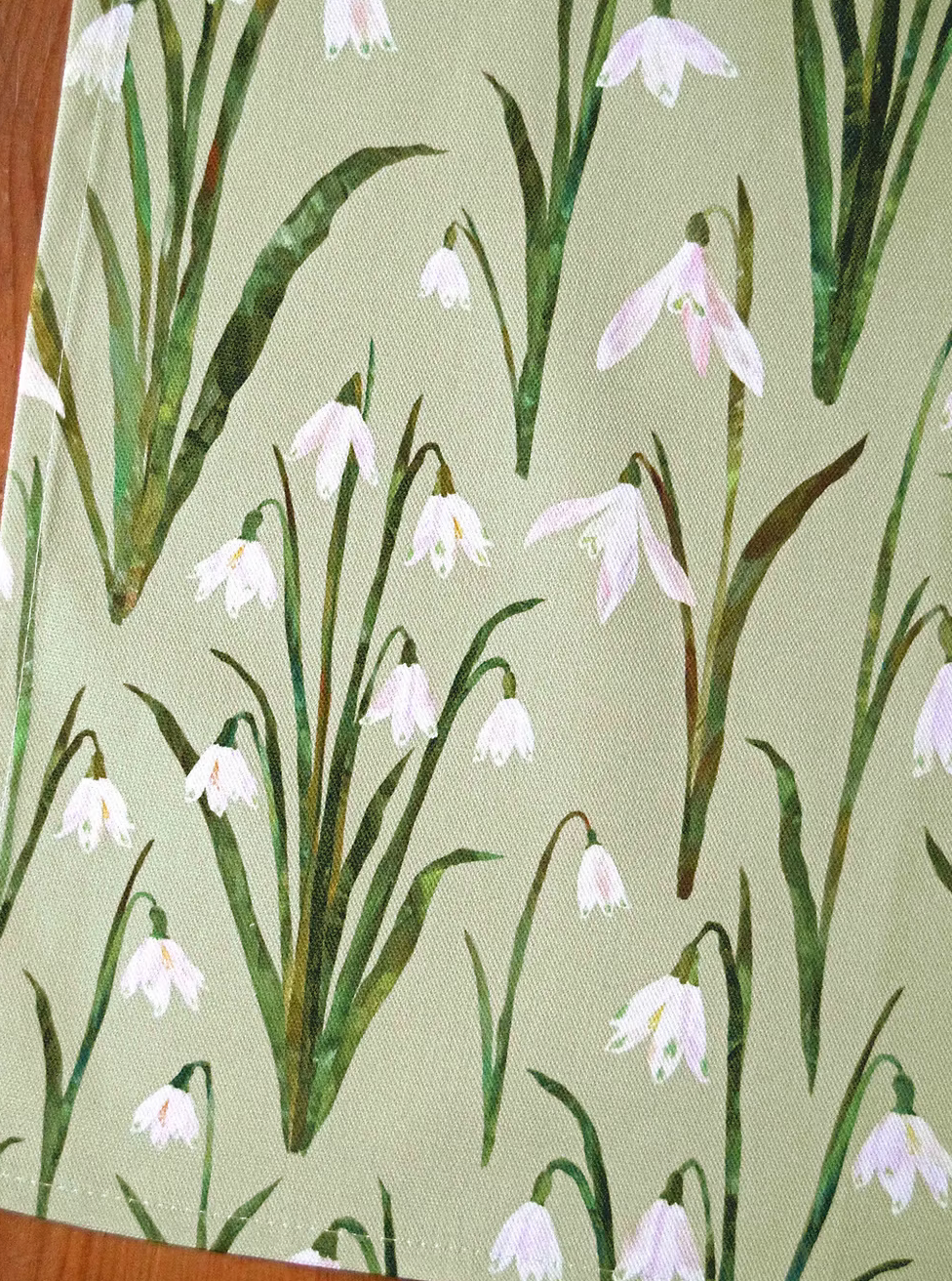 close up of snowdrops tea towel by Freya Snow on a light green background