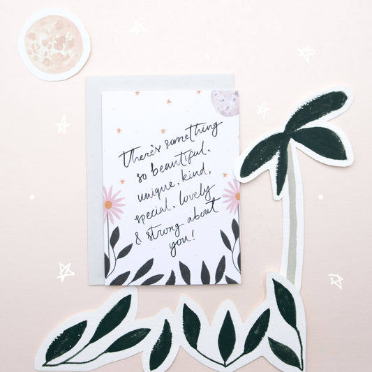 Motivational card with floral design and decorative leaves on a light pink background