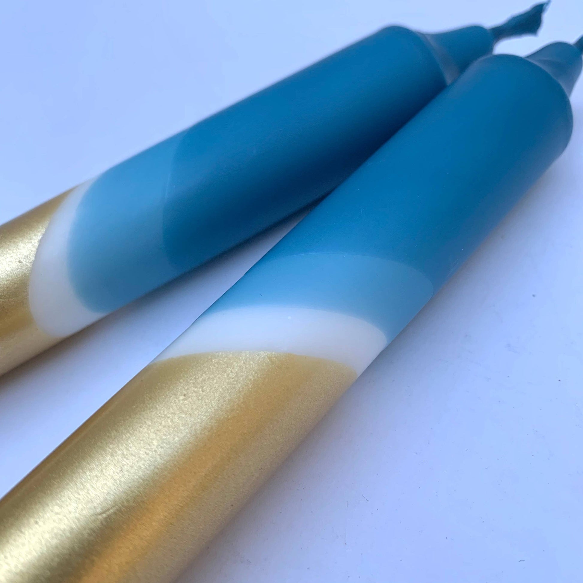 close up of teal blue and gold candles by The Singing Rabbit